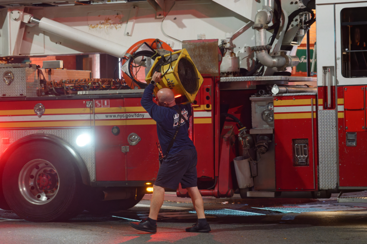 A firefighter carries an exhaust fan to the building. Photo: Carl Glassman/Tribeca Trib